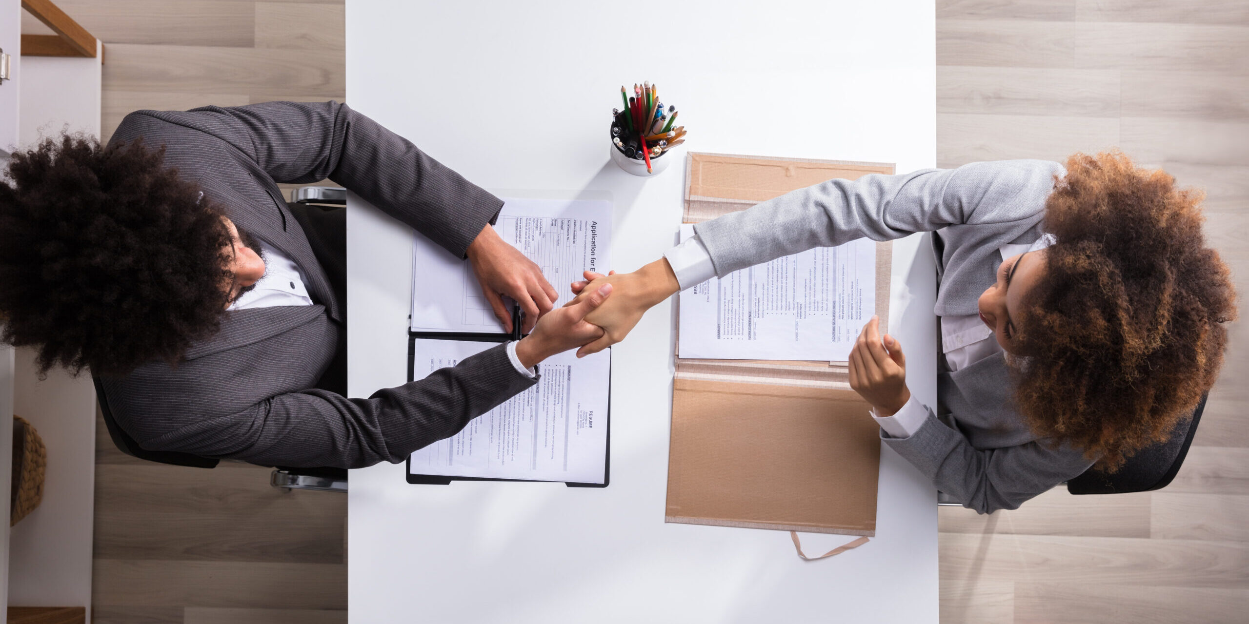 Elevated View Of A Male Manager Shaking Hands With Female Applicant At Workplace